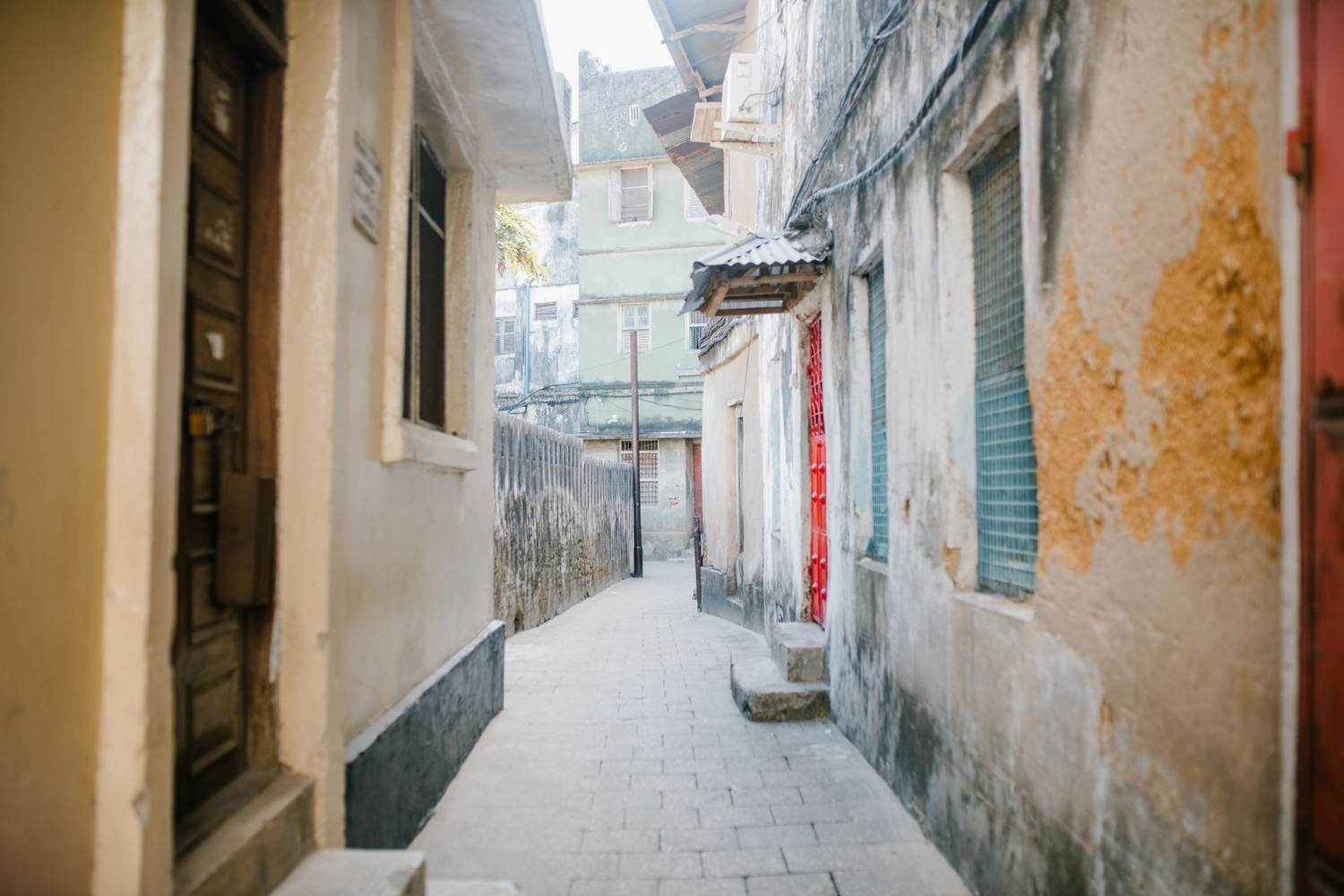 A narrow historic lane in Stone Town, Zanzibar, with carved doors and coral-stone walls